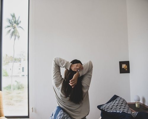 A person stretching softly next to a window in the morning light