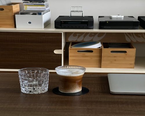 A glass of water and a coffee cup on a neat wooden desk