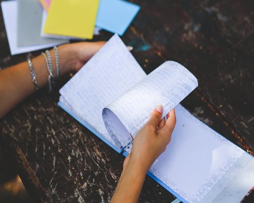 Hands writing in a personal journal on a wooden table